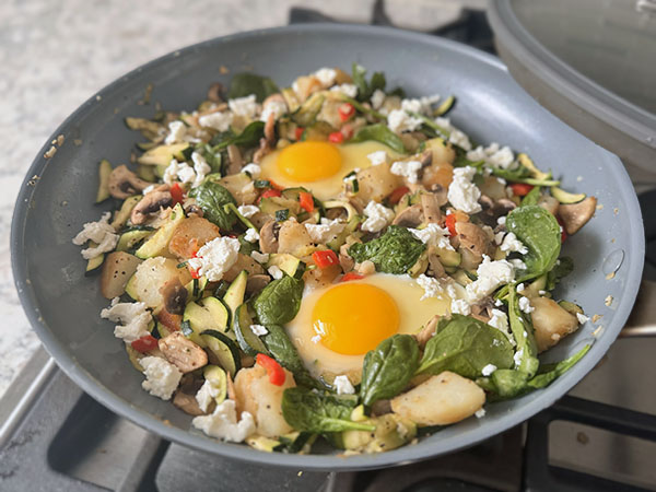 Яйца, добавленные к овощному грибному хашу, жарятся в сковороде.