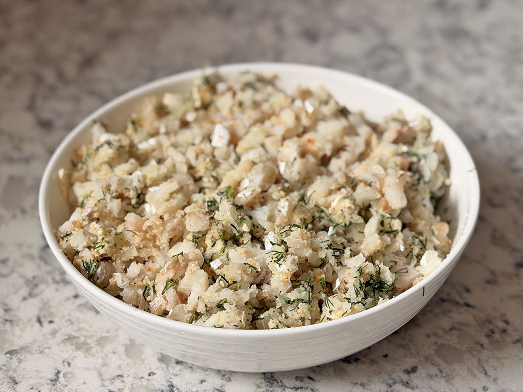 Cod fish cake mixture fully combined in a bowl, showing diced cod mixed with breadcrumbs, dill, onion, butter, and egg whites ready for shaping.