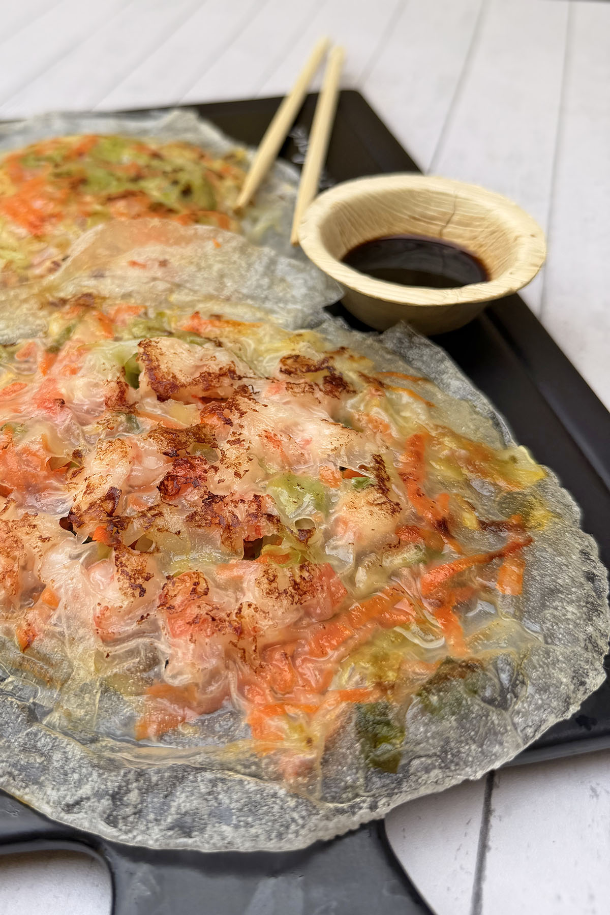 Crispy rice paper shrimp and vegetable pancake on a serving board.