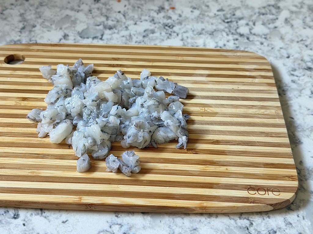 Chopped raw shrimp on a cutting board.