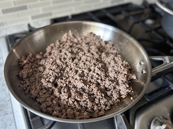 Ground beef browning in a skillet.