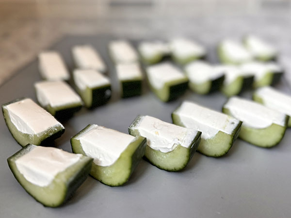 English cucumber halves filled with cream cheese cut into bite-sized pieces.