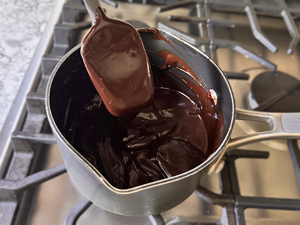 Chocolate truffle mixture on the stove top with a rubber spatula coated in chocolate.