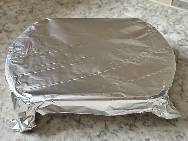 Rice in a baking dish covered with foil.