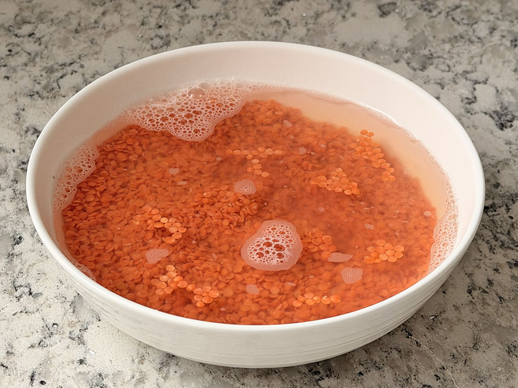 Dry red lentils in a bowl covered with hot water to soften.