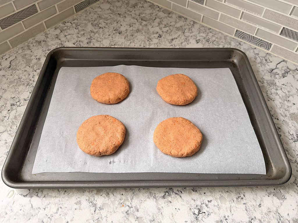 Dough divided into portions and shaped into buns on a parchment-lined baking sheet.