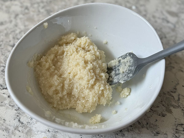 Mixed fine coconut, coconut milk and white chocolate mixture in a bowl.