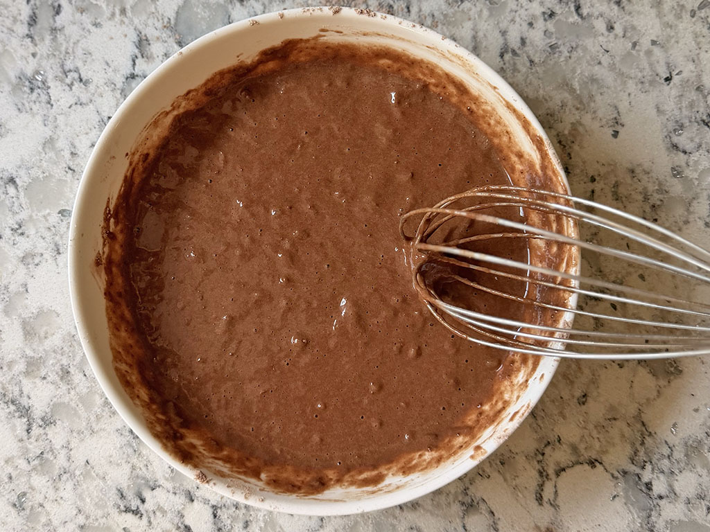 Banana mixture and dry ingredients whisked together into a smooth chocolate batter for flourless chocolate banana cake.