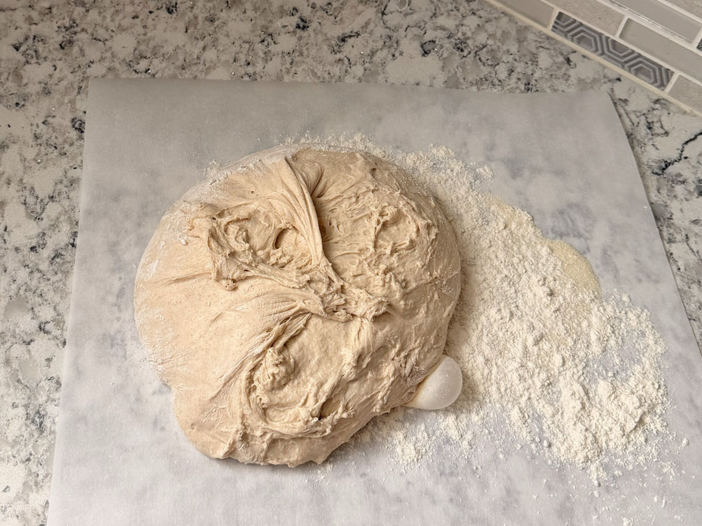 Dough placed on a lightly floured surface, ready for pre-shaping after bulk fermentation.