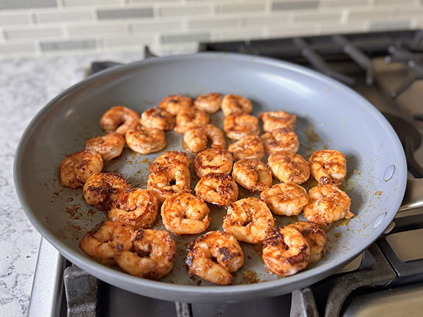 Cooked shrimp in a skillet on the stove top.