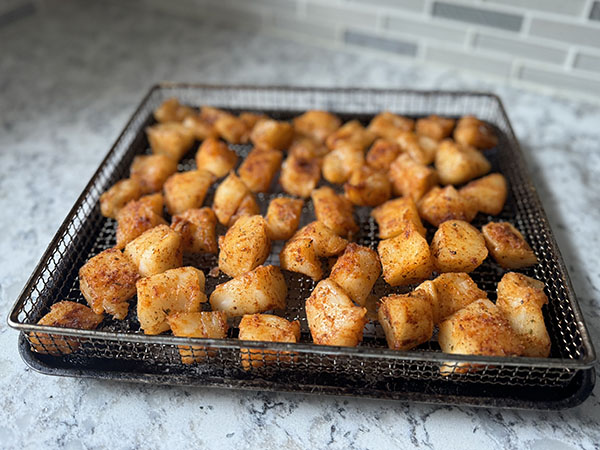 Seasoned cod pieces on a baking sheet with a rack.