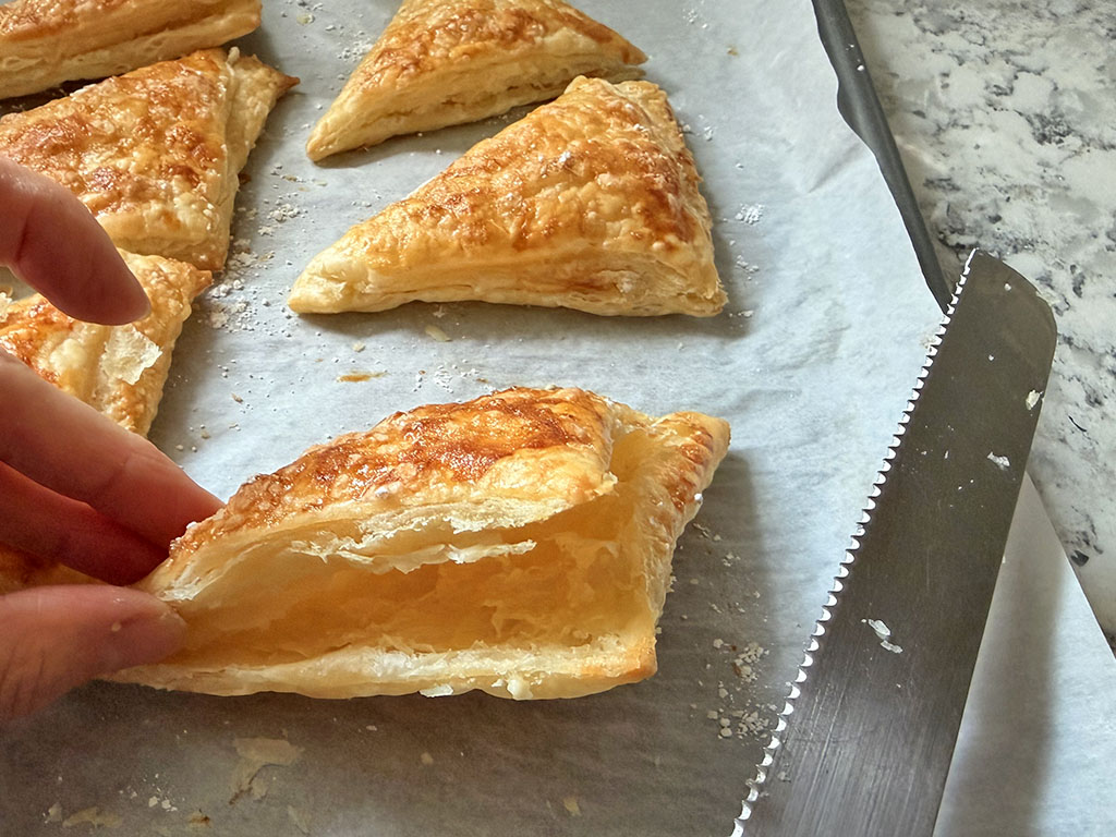 Baked puff pastry triangles sliced open and ready for filling.
