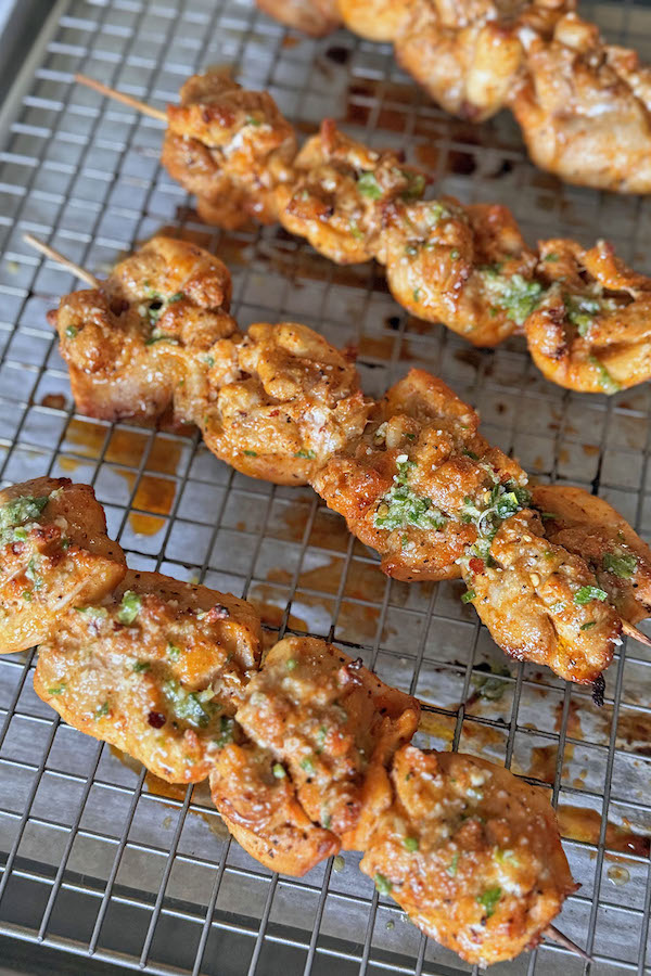 Juicy chicken skewers finished with garlicky Parmesan sauce on a baking rack.