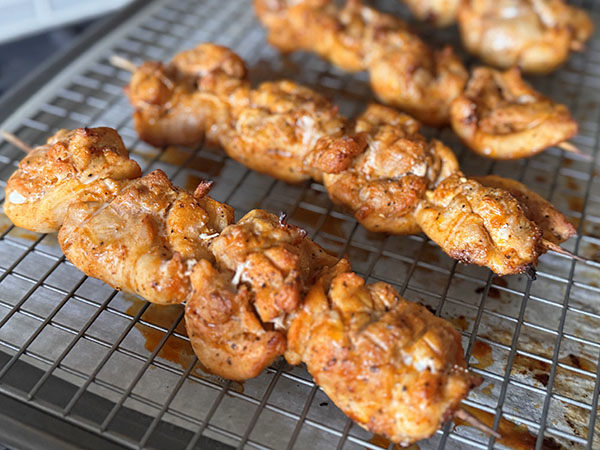 Baked chicken thigh skewers sitting on a baking rack.