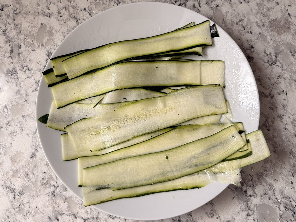 Zucchini ribbons on a plate tossed with oil.