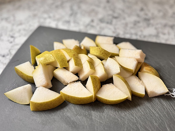 Pear cut into bite-size pieces on a cutting board.