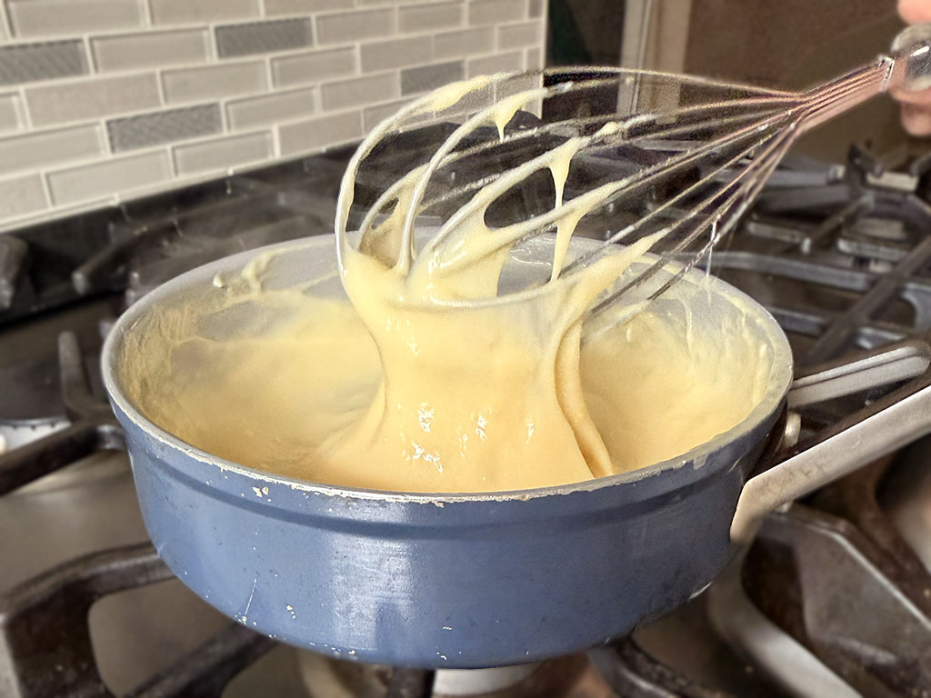 Ванильный крем готовится в кастрюле на среднем огне, его постоянно помешивают до загустения.