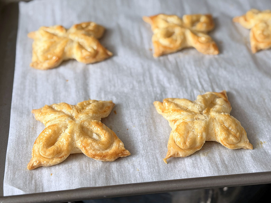 Испечённые слоёные цветочки золотистые и пышные на противне.