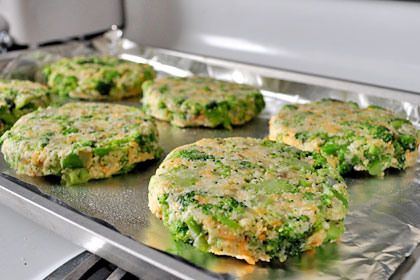 Shaped broccoli patties on a foil lined baking sheet ready for oven.