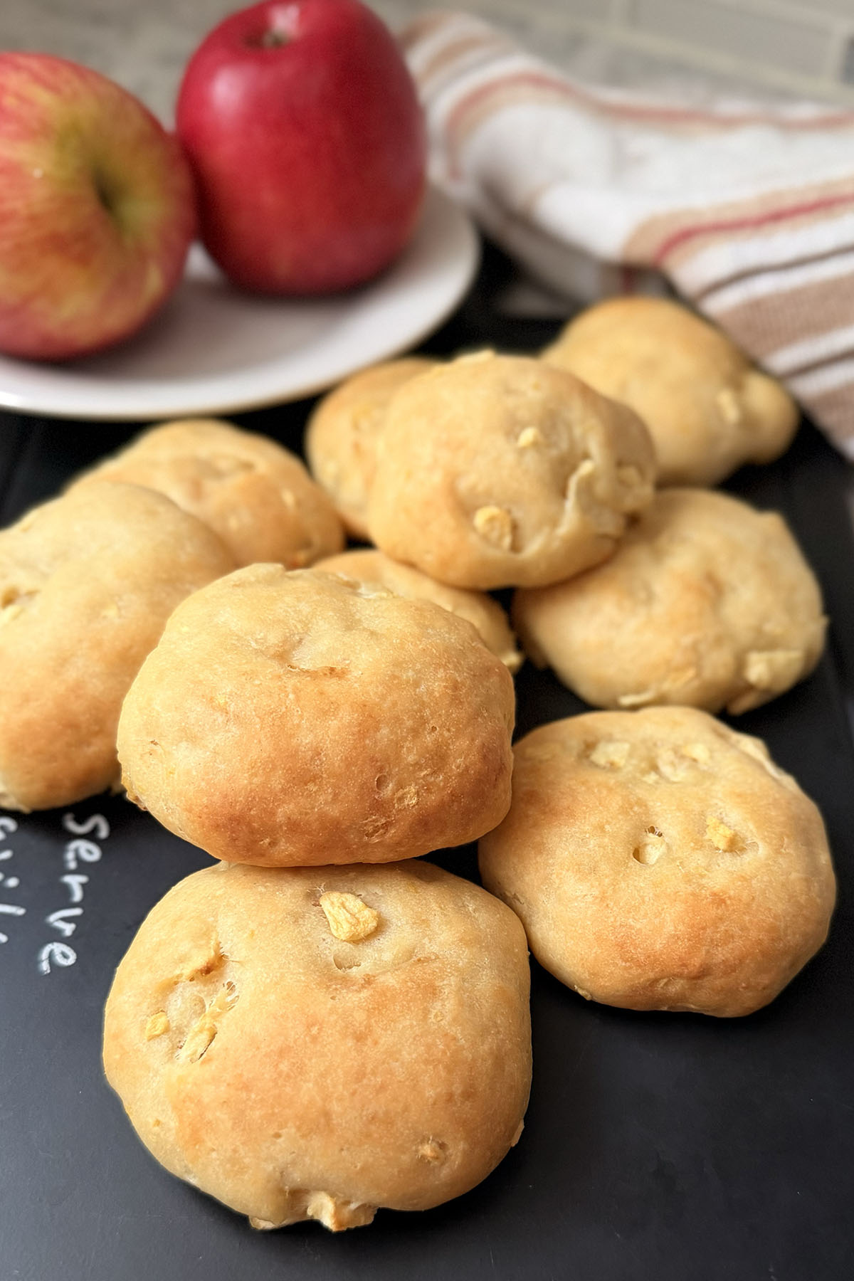 Baked apple and farmer’s cheese cookies on a serving board with apples in the background.