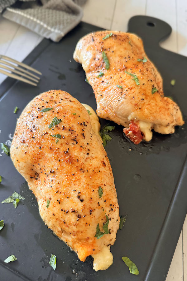 Baked chicken stuffed with spinach, mozzarella & sun-dried tomatoes on a serving board