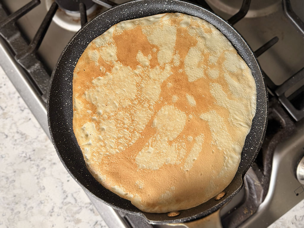 Banana crepe flipped and cooking on the second side until lightly browned.